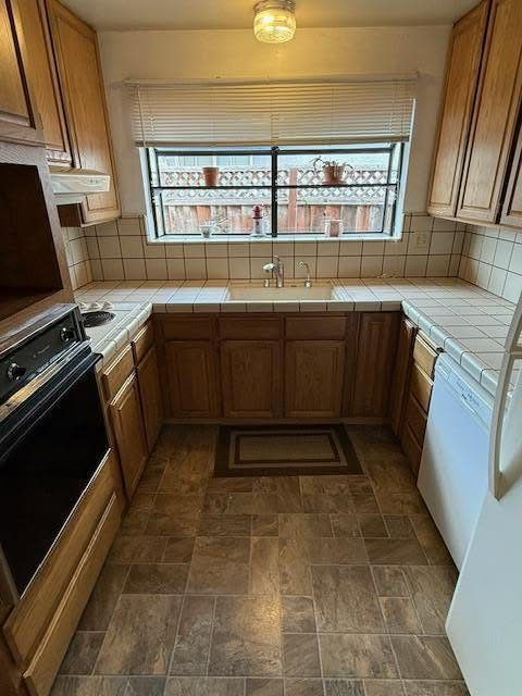 Original galley kitchen with tile counters and oak cabinets